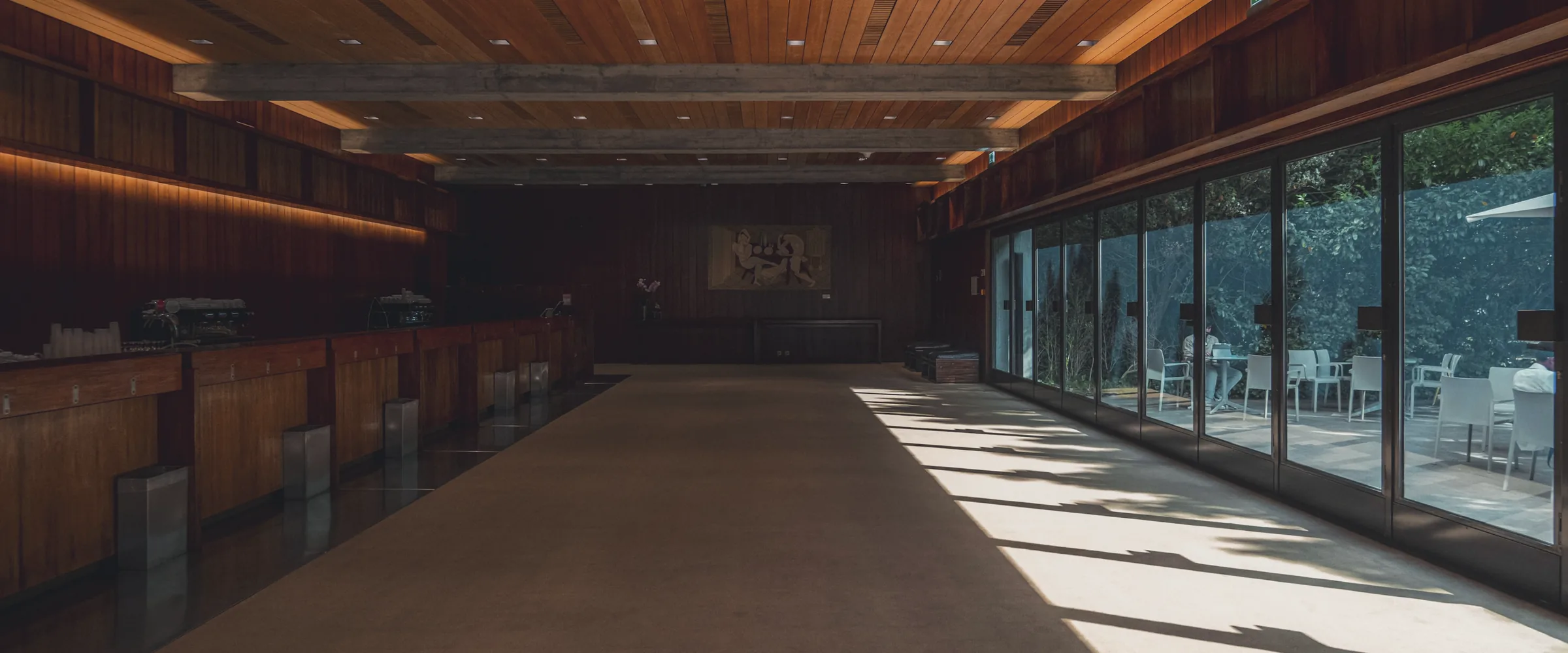 A dark timber hall opening onto a wall of daylight.